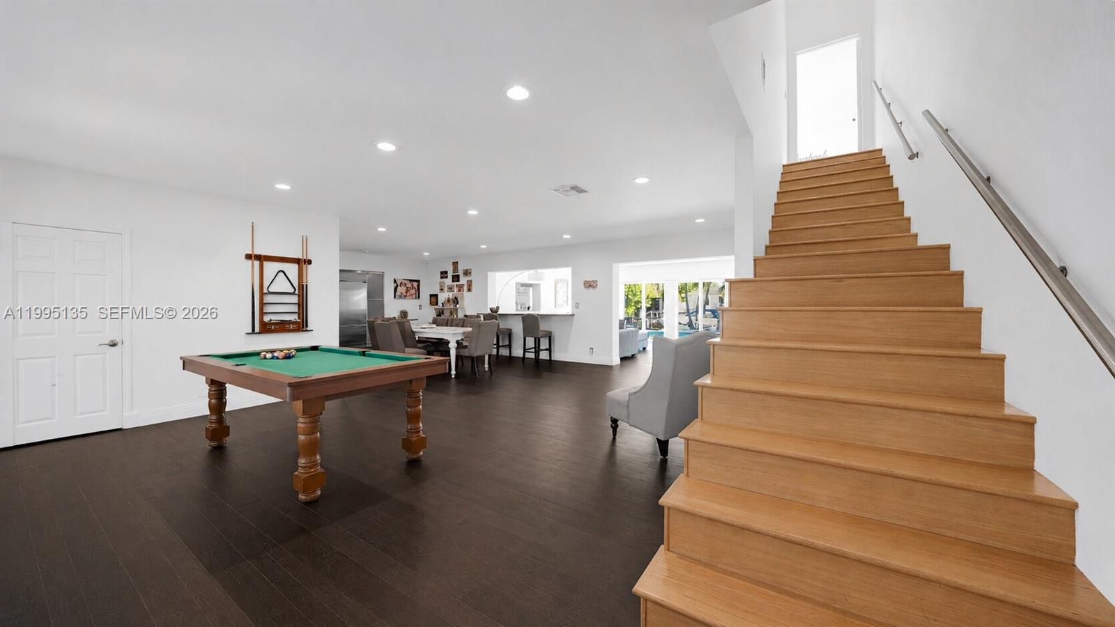 A spacious room features a pool table, wooden staircase, and dark hardwood flooring — 1895 NE 118th Rd, North Miami FL 33181, NORTH MIAMI, FL