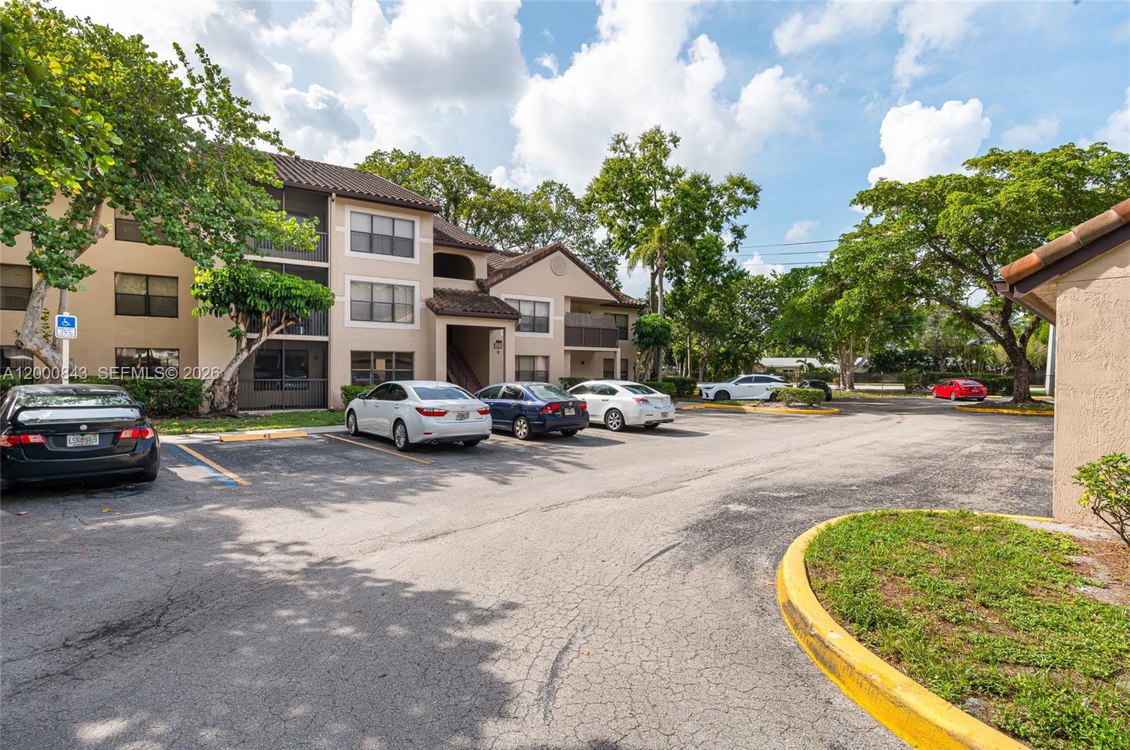 A multi-story apartment building with a parking lot in the foreground under a cloudy sky — 4581 W Mcnab Rd # 28, Pompano Beach FL 33069, POMPANO BEACH, FL