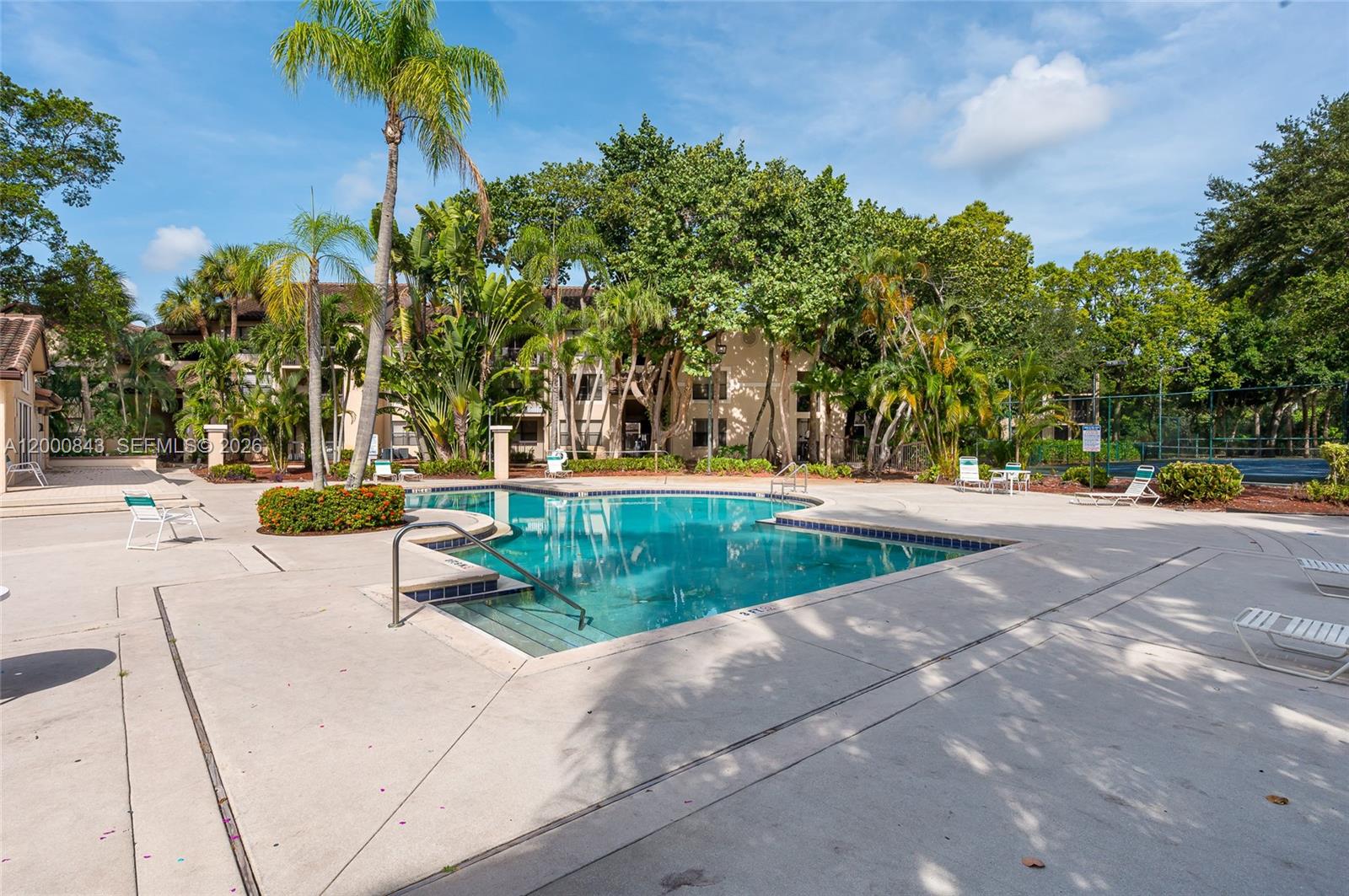 A swimming pool with a metal handrail sits on a concrete deck surrounded by trees — 4581 W Mcnab Rd # 28, Pompano Beach FL 33069, POMPANO BEACH, FL
