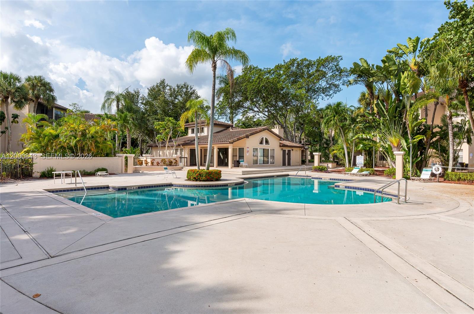 A swimming pool sits in front of a clubhouse surrounded by palm trees and landscaping — 4581 W Mcnab Rd # 28, Pompano Beach FL 33069, POMPANO BEACH, FL