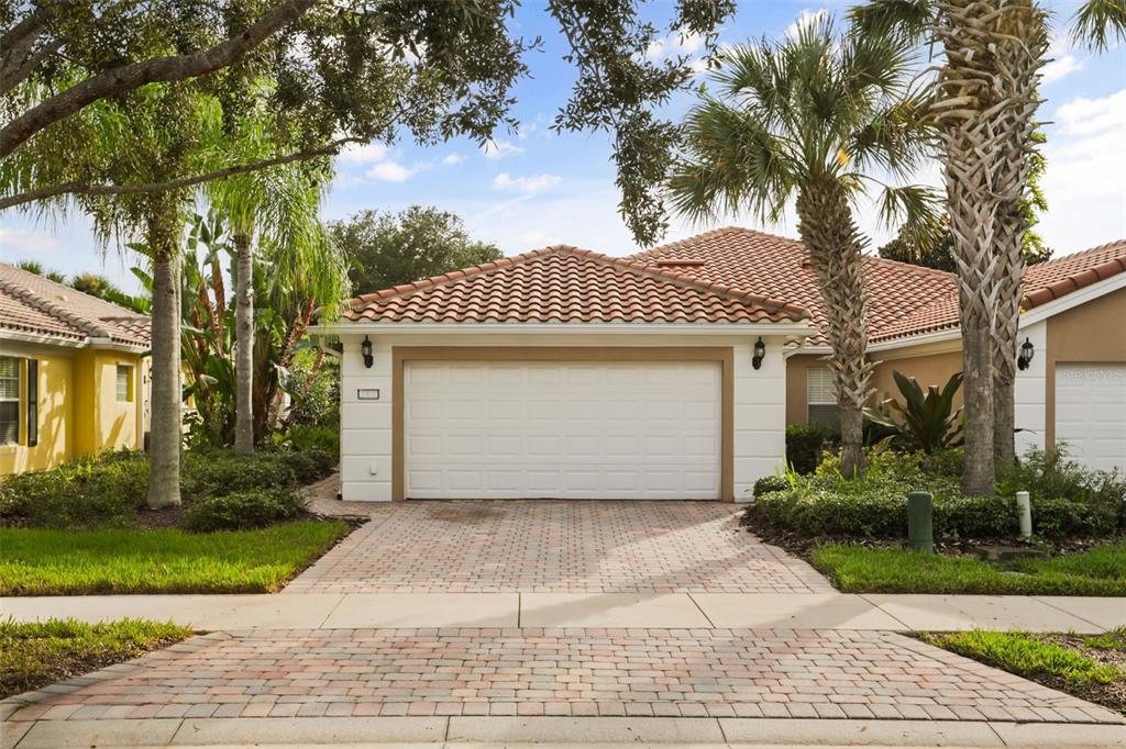 A single-story house exterior featuring a white garage door, tiled roof, and paved driveway — 11972 KAJETAN LANE, ORLANDO, FL