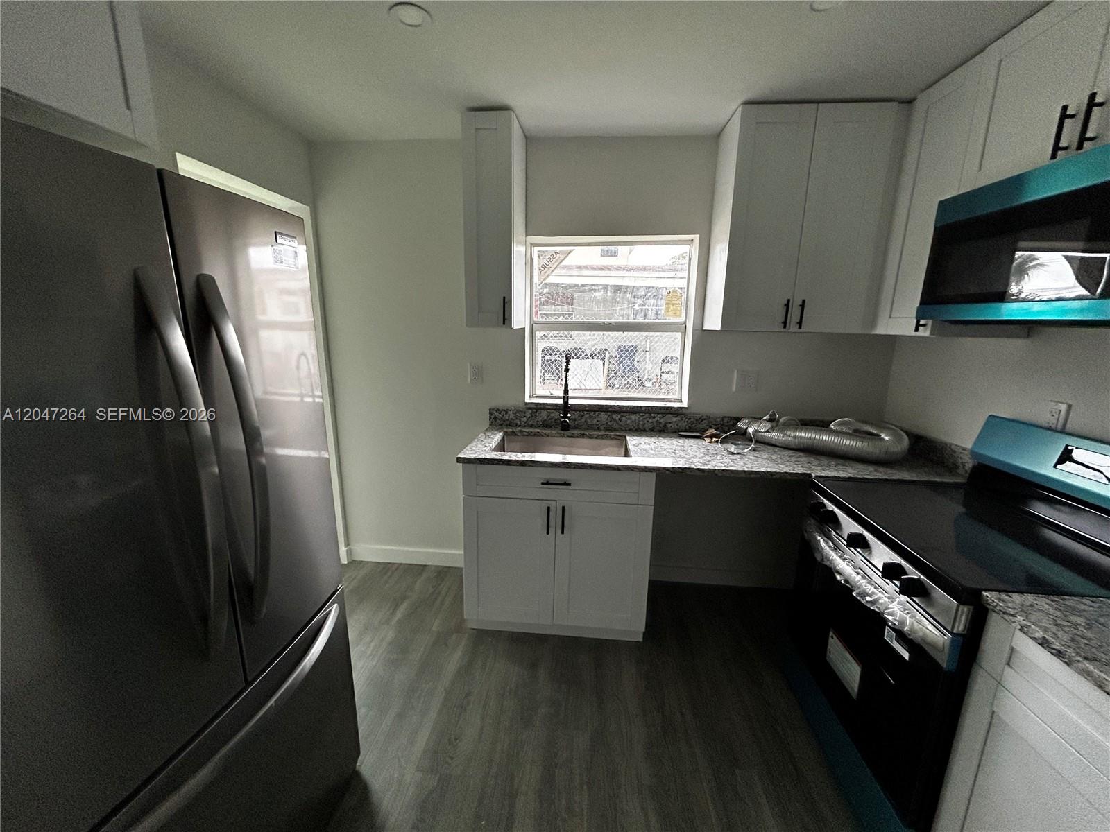 A kitchen features white cabinets, granite countertops, stainless steel appliances, and wood-look flooring — 4429 SW 21st St, West Park FL 33023, WEST PARK, FL