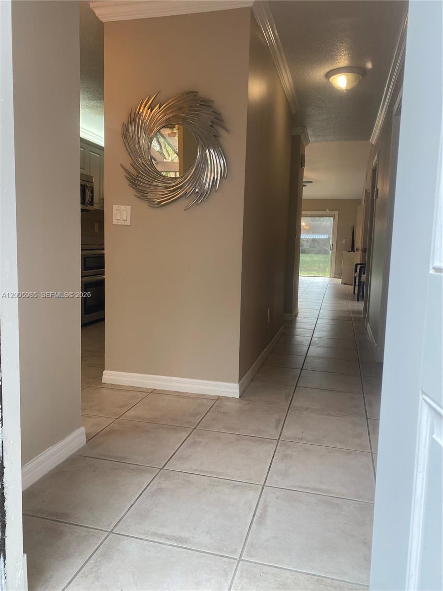 A tiled hallway leads past a wall with a decorative mirror toward a rear exit — 803 SW 119th Way, Davie FL 33325, DAVIE, FL