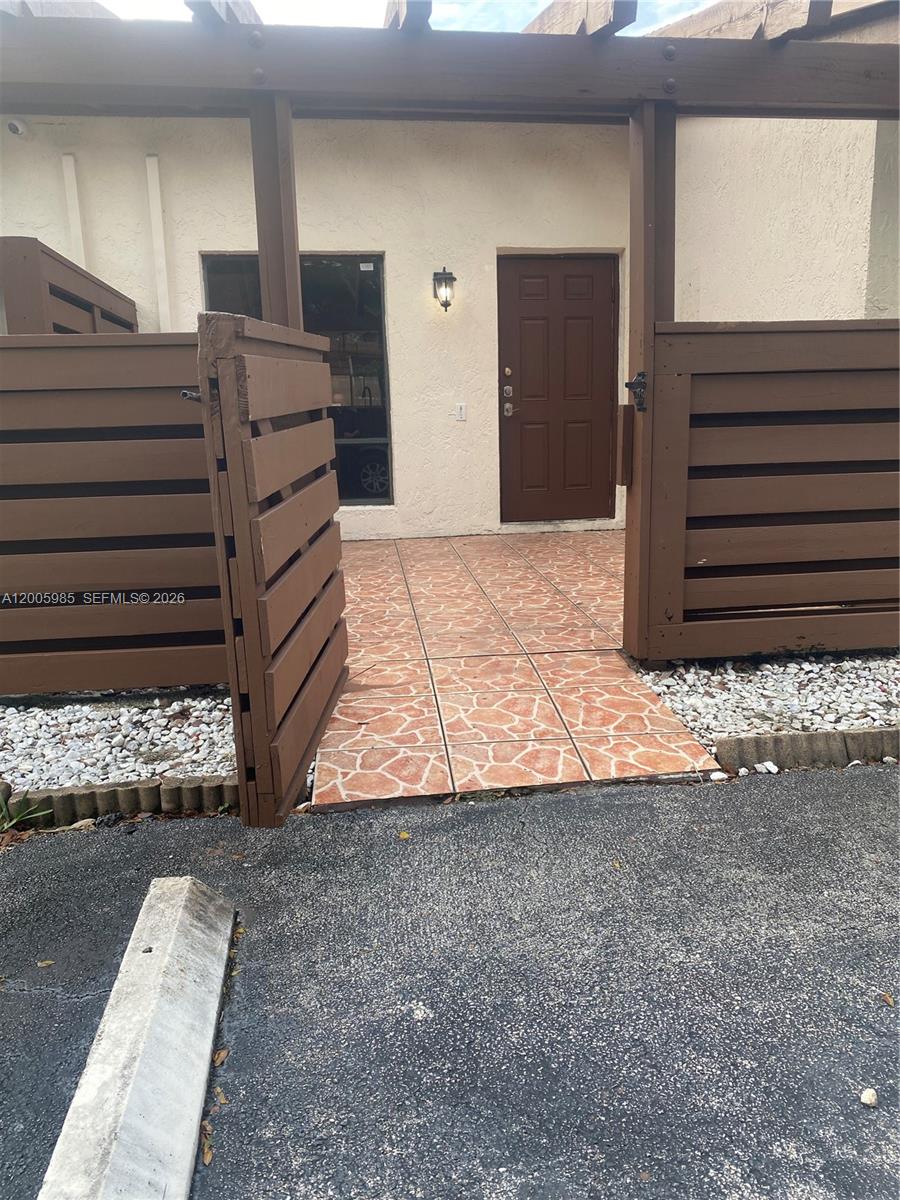 A brown door and window are set behind a wooden privacy fence and pergola — 803 SW 119th Way, Davie FL 33325, DAVIE, FL