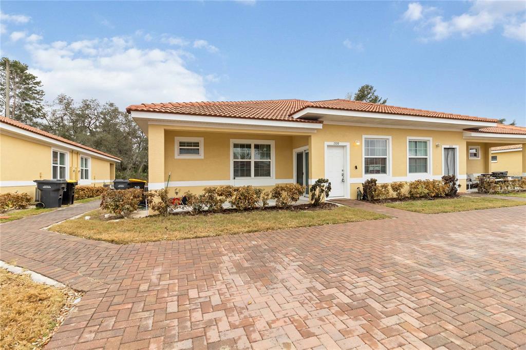 A yellow single-story duplex with a tiled roof and a brick paver driveway — 1599 CUMIN DRIVE UNIT 1599, KISSIMMEE, FL