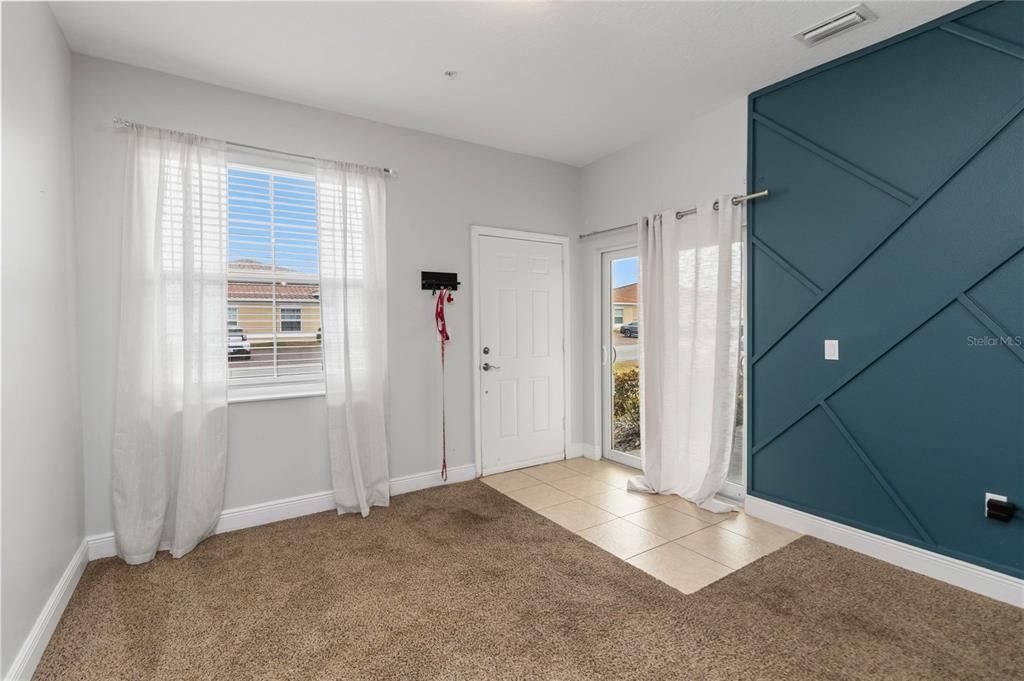 A room with carpeted flooring, a tiled entryway, a window, and a blue accent wall — 1599 CUMIN DRIVE UNIT 1599, KISSIMMEE, FL