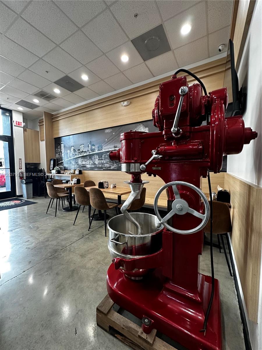 A large red industrial dough mixer stands in a restaurant dining area with tables — Confidential, Coconut Grove FL 33133, COCONUT GROVE, FL
