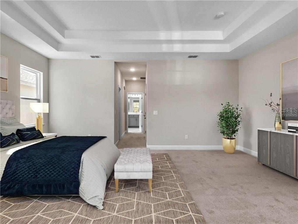 A bedroom features a tray ceiling, neutral walls, carpeted flooring, and a bed with blue bedding — 913 TALON PLACE, WINTER SPRINGS, FL