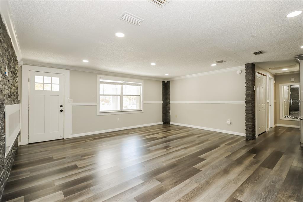 A living room with light gray walls, wood-look flooring, recessed lighting, and stone accent pillars — 3147 36TH AVENUE N, ST PETERSBURG, FL
