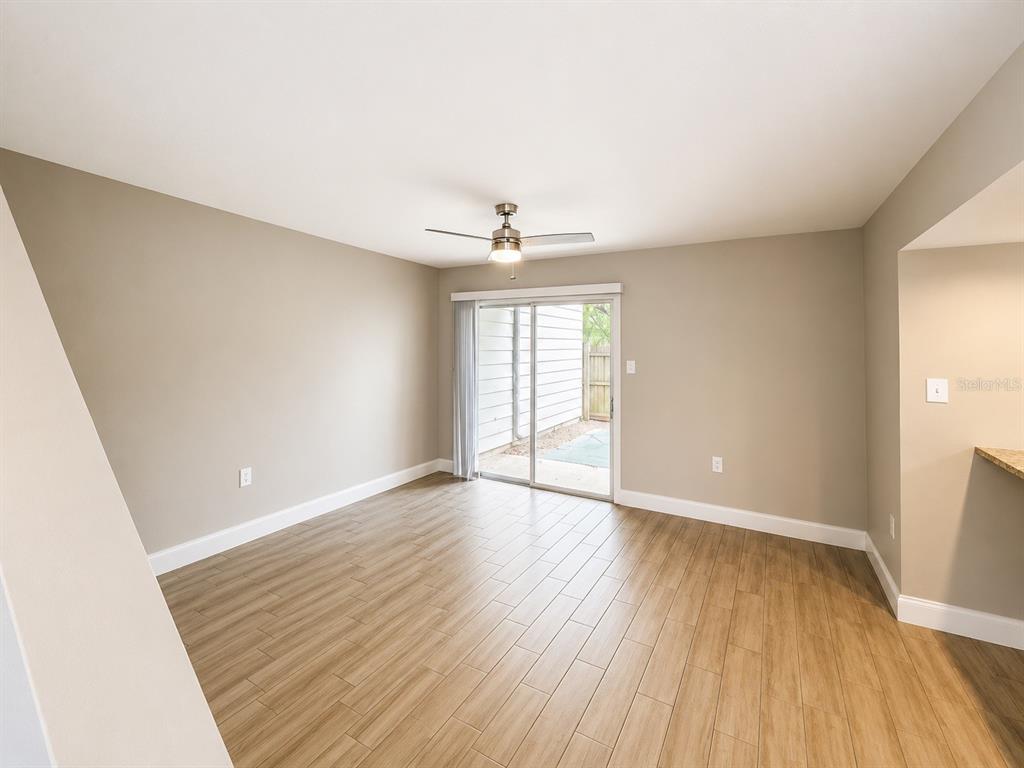 An empty room with light wood-look tile flooring, a ceiling fan, and sliding glass doors — 3922 CRAYRICH CIRCLE UNIT C-4, ORLANDO, FL