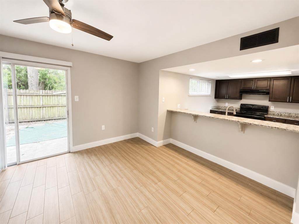 A dining area with wood-look tile flooring opens to a kitchen with dark cabinets — 3922 CRAYRICH CIRCLE UNIT C-4, ORLANDO, FL
