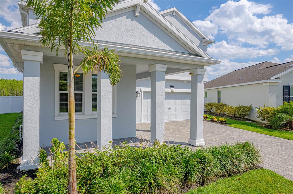 A light-colored house exterior features a covered porch, a paved driveway, and a garage — 3032 PRELUDE LANE, KISSIMMEE, FL