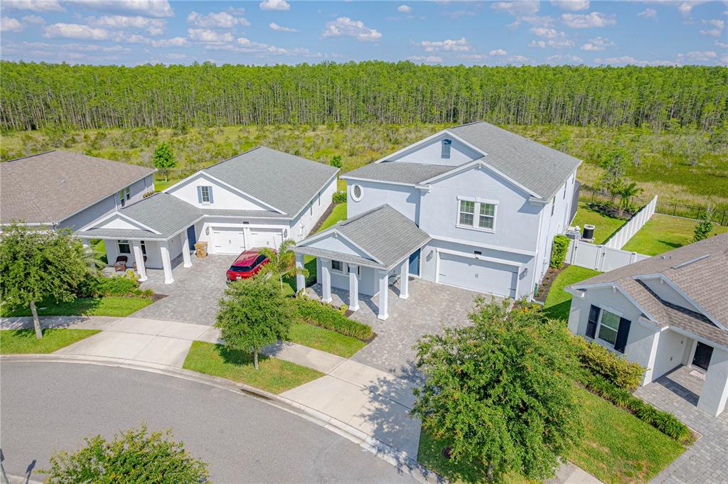 An aerial view shows three suburban houses with gray roofs, paved driveways, and green lawns — 3032 PRELUDE LANE, KISSIMMEE, FL