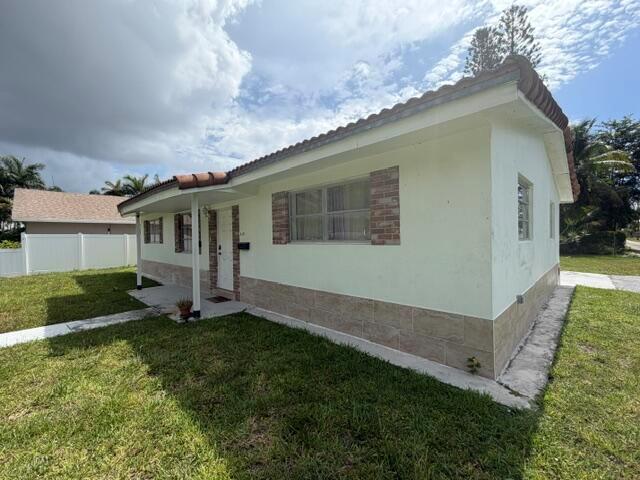 A light-colored, single-story house features a tiled roof, brick accents, and a concrete walkway — 210 NE 5th Avenue, Dania Beach FL 33004, DANIA BEACH, FL