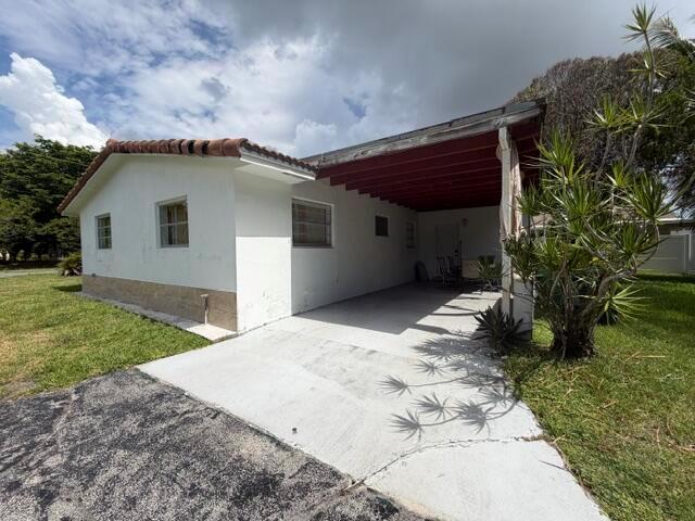 A single-story house with a white exterior, a red-roofed carport, and a concrete driveway — 210 NE 5th Avenue, Dania Beach FL 33004, DANIA BEACH, FL