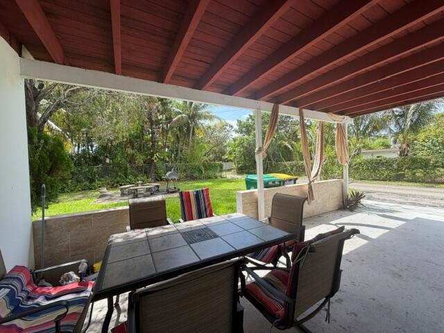 A covered patio features a dining table with chairs overlooking a grassy backyard — 210 NE 5th Avenue, Dania Beach FL 33004, DANIA BEACH, FL