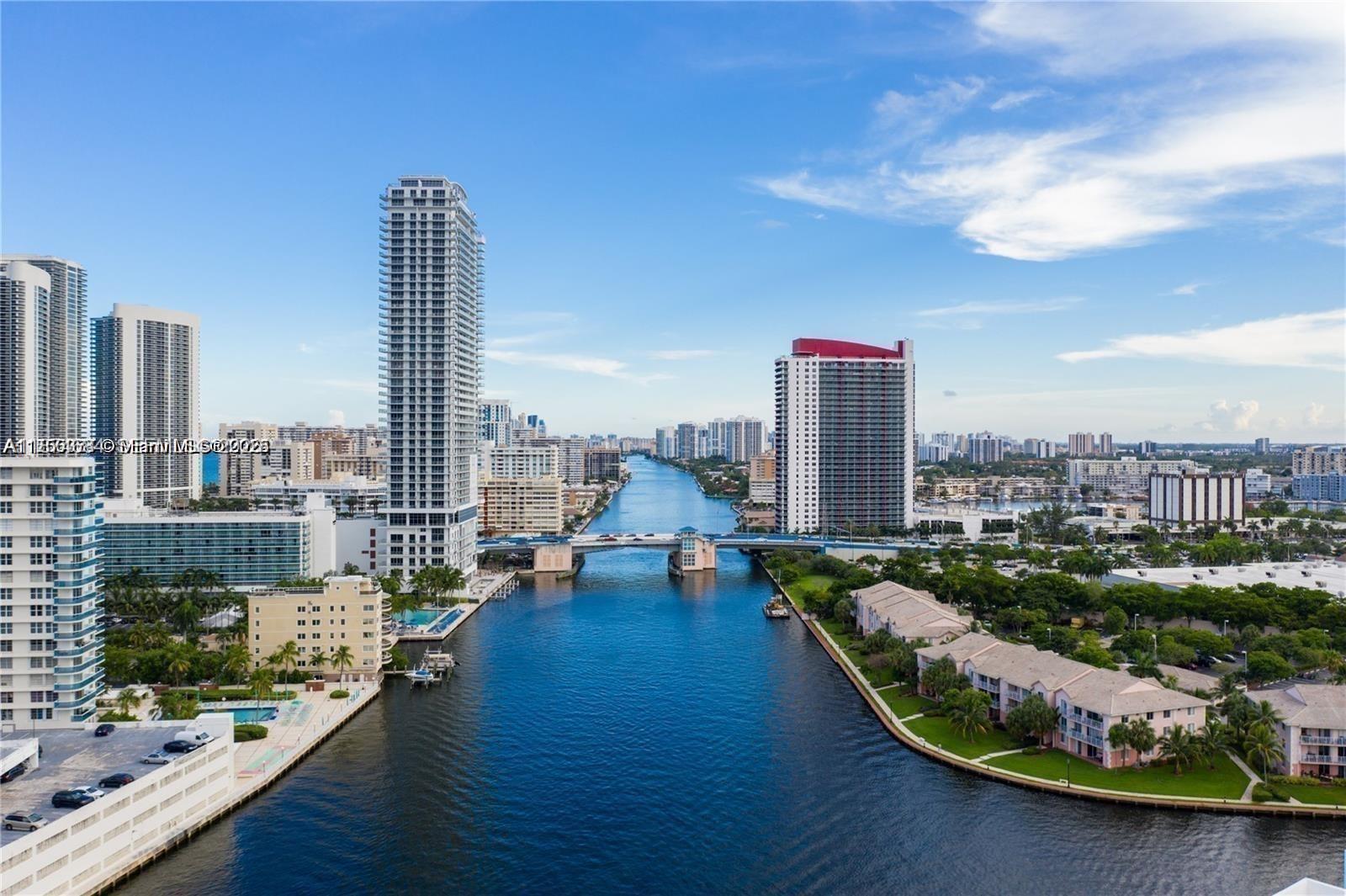 An aerial view shows a waterway flowing between high-rise buildings and a bridge in Miami — 1000 Parkview Dr # 805, Hallandale Beach FL 33009, HALLANDALE BEACH, FL