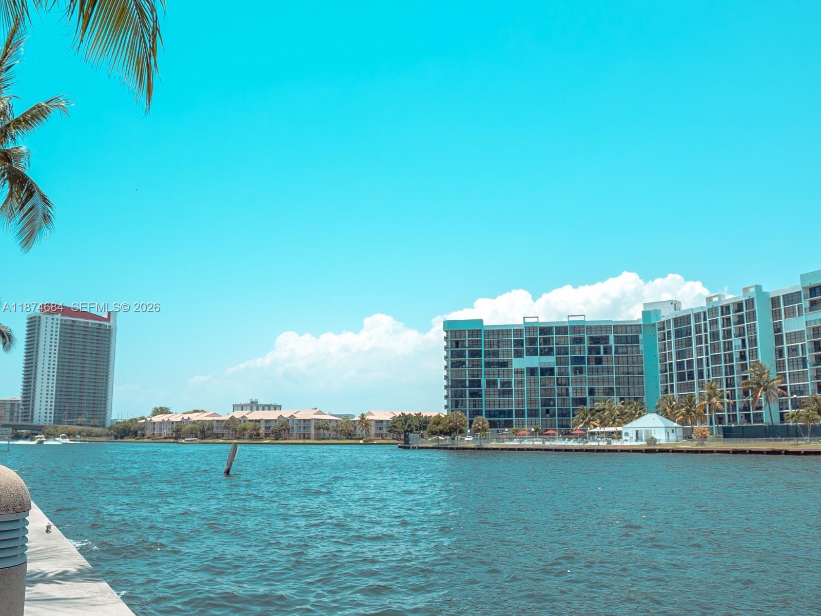 A view of a waterway with large apartment buildings and palm trees under a blue sky — 1000 Parkview Dr # 805, Hallandale Beach FL 33009, HALLANDALE BEACH, FL