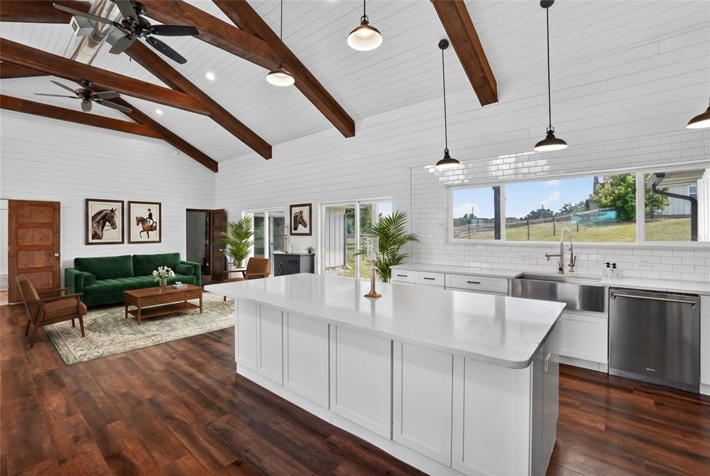 A bright open-concept kitchen and living area features white shiplap walls, wood beams, and hardwood floors — 13009 NW 123RD PLACE, ALACHUA, FL