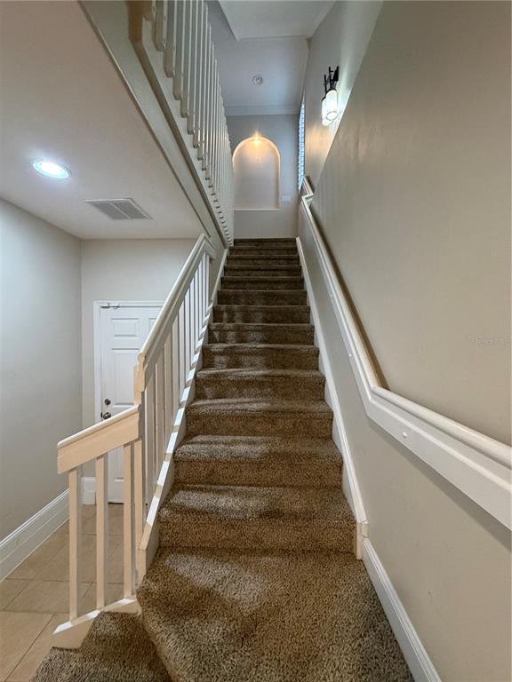 A carpeted staircase with white railings leads to an upper landing with an arched niche — 1325 COMMON WAY ROAD, ORLANDO, FL