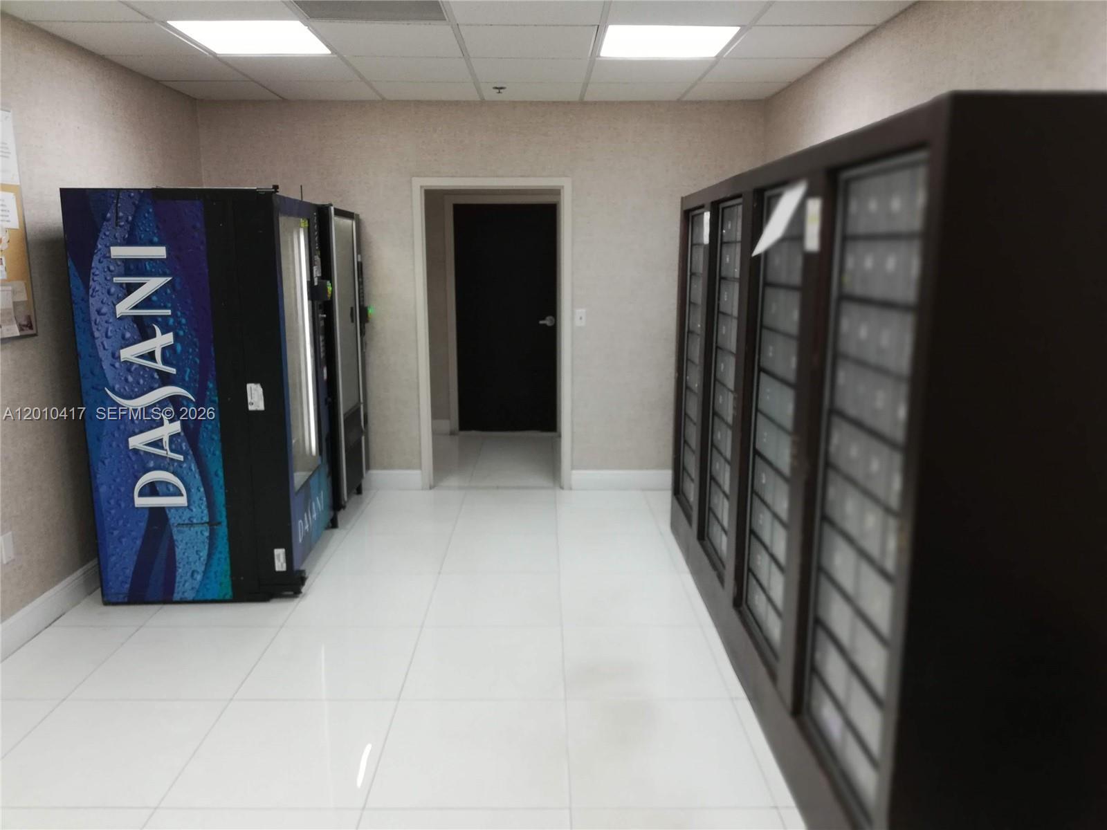 A hallway features white tiled floors, a Dasani vending machine, and a wall of mailboxes — 12550 Biscayne Blvd # 605, North Miami FL 33181, NORTH MIAMI, FL
