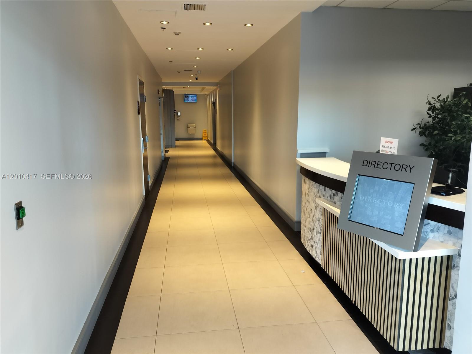 A modern office lobby features a directory kiosk, tiled flooring, and a long hallway — 12550 Biscayne Blvd # 605, North Miami FL 33181, NORTH MIAMI, FL