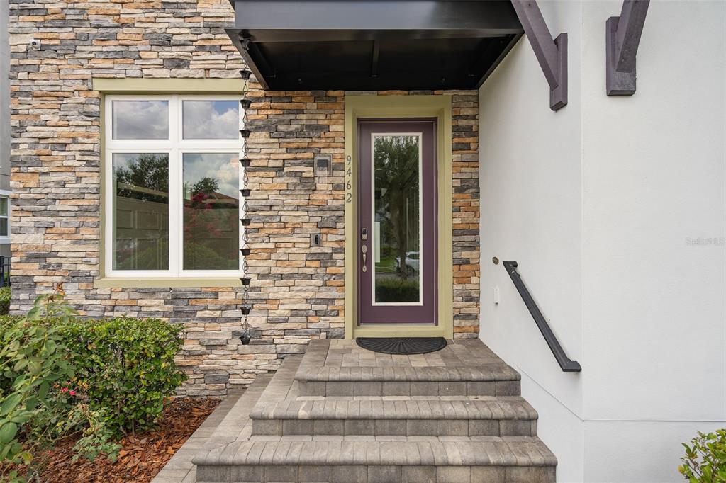 A stone-faced house exterior features a purple front door, a black awning, and stone steps — 9462 BECKER COURT, ORLANDO, FL