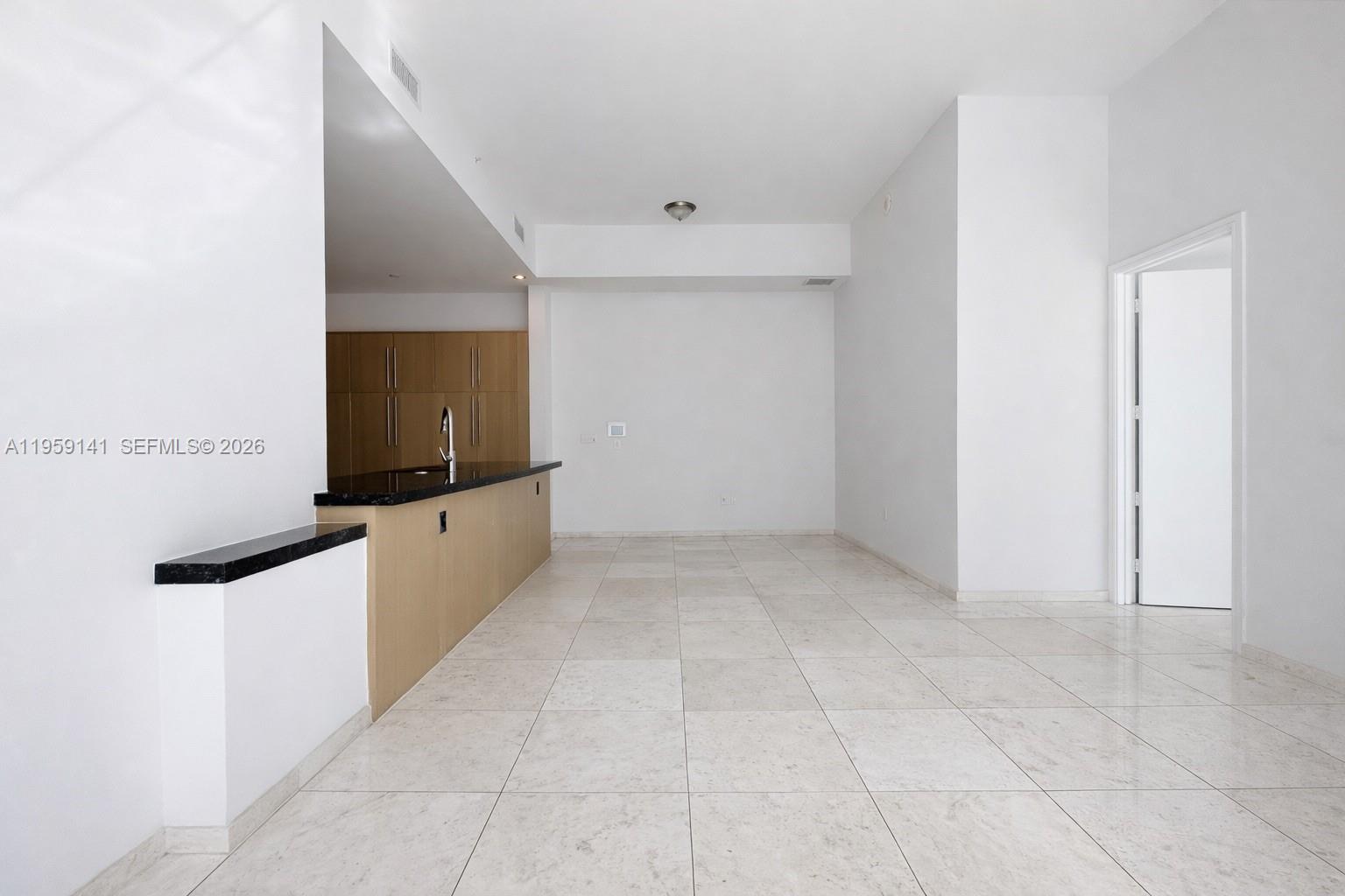 An open-concept kitchen and living area features light-colored tile flooring and light wood cabinetry — 900 Brickell Key Blvd # 2405, Miami FL 33131, MIAMI, FL