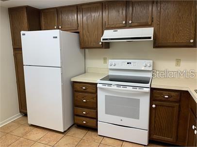 A kitchen features wood cabinets, a white refrigerator, and a white electric range — 7360 ULMERTON ROAD UNIT 4D, LARGO, FL