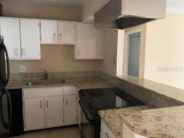 A kitchen features white cabinets, granite countertops, a stainless steel range, and a range hood — 120 W AMERICA STREET UNIT 7, ORLANDO, FL