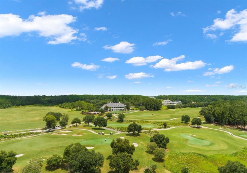 An aerial view shows a golf course with a large clubhouse surrounded by trees — 19612 STERLING BLUFF WAY, BROOKSVILLE, FL