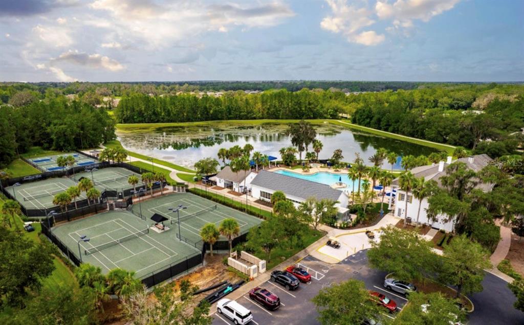 An aerial view shows tennis courts, a swimming pool, a clubhouse, and a parking lot — 19612 STERLING BLUFF WAY, BROOKSVILLE, FL