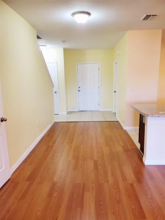 An interior view showing a foyer with wood-look flooring, light yellow walls, and a white door — 9907 HOUND CHASE DRIVE, GIBSONTON, FL