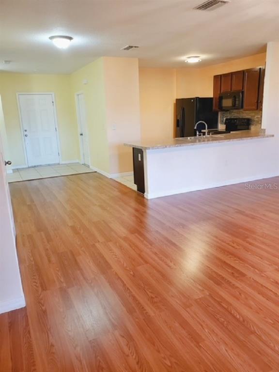 An open-concept kitchen with a breakfast bar overlooks a living area with wood-look flooring — 9907 HOUND CHASE DRIVE, GIBSONTON, FL