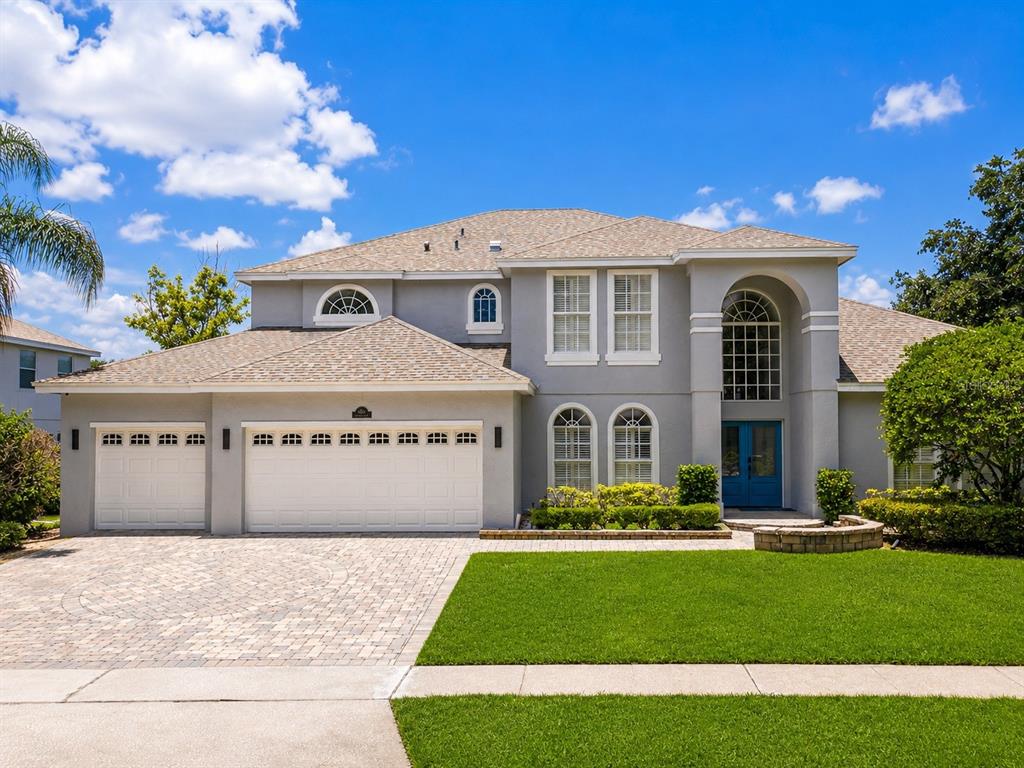A two-story gray house with a three-car garage, arched windows, and a paved driveway — 2106 STILLINGTON STREET, ORLANDO, FL