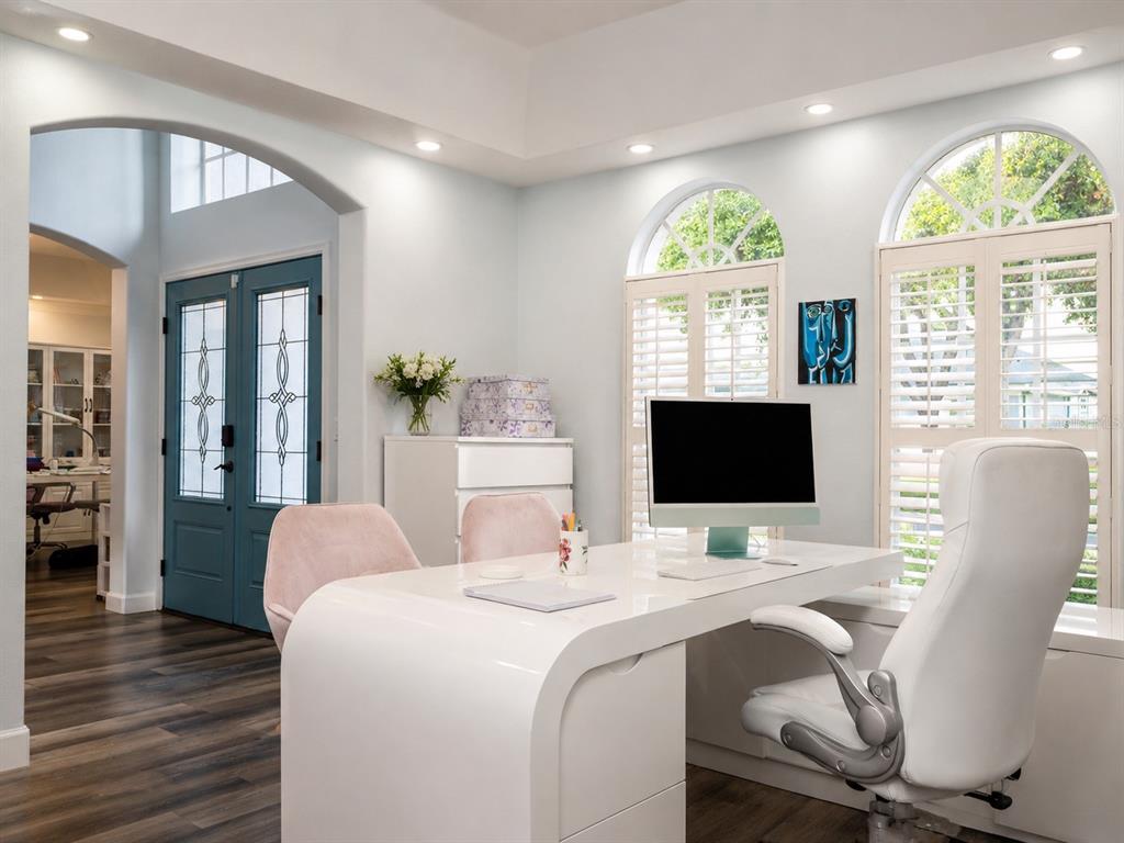 A modern home office features a white curved desk, pink chairs, and arched windows — 2106 STILLINGTON STREET, ORLANDO, FL