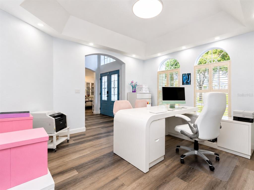 A home office features a white desk, wood-look flooring, and arched windows with shutters — 2106 STILLINGTON STREET, ORLANDO, FL