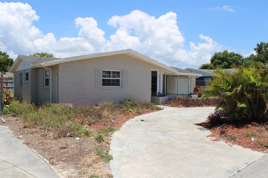 A single-story house with a beige exterior, a concrete driveway, and a small front yard — 3314 COLUMBUS DRIVE, HOLIDAY, FL