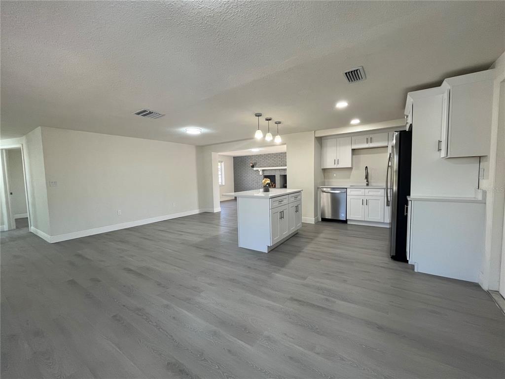 A kitchen with white cabinets, a center island, and gray wood-look flooring — 3314 COLUMBUS DRIVE, HOLIDAY, FL