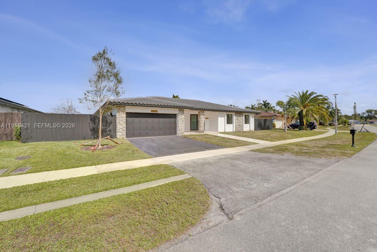 A single-story house with a dark garage door, stone accents, and a paved driveway — 16653 Golfview Dr, Weston FL 33326, WESTON, FL