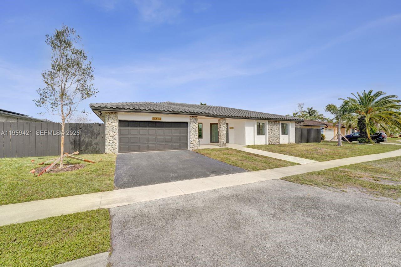 A single-story house with a gray garage, stone accents, and a paved driveway — 16653 Golfview Dr, Weston FL 33326, WESTON, FL