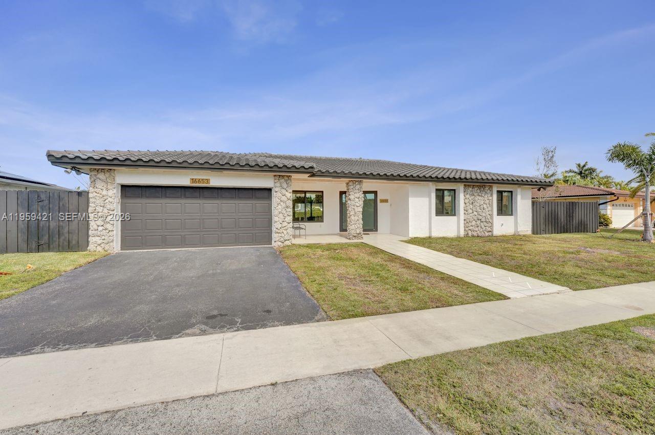 A single-story house with a two-car garage, stone accents, and a tiled roof — 16653 Golfview Dr, Weston FL 33326, WESTON, FL