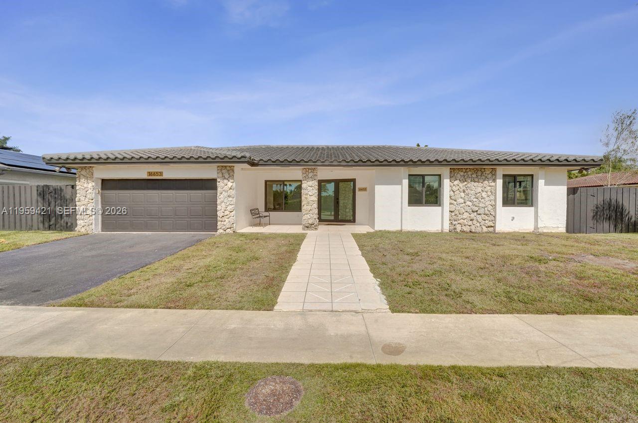 A single-story house with a white stucco facade, stone accents, and a dark tile roof — 16653 Golfview Dr, Weston FL 33326, WESTON, FL