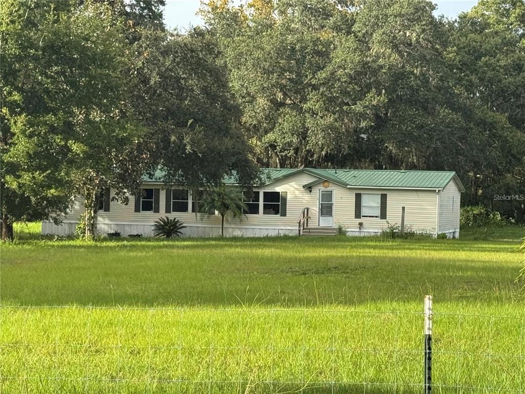 A single-story manufactured home with a green metal roof sits on a grassy lot — 15425 TROUSDALE STREET, CLERMONT, FL