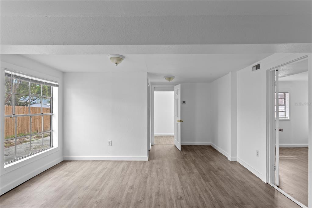 An empty room with white walls, wood-look flooring, and a large window facing a fence — 4103 N HOWARD AVENUE UNIT A, TAMPA, FL