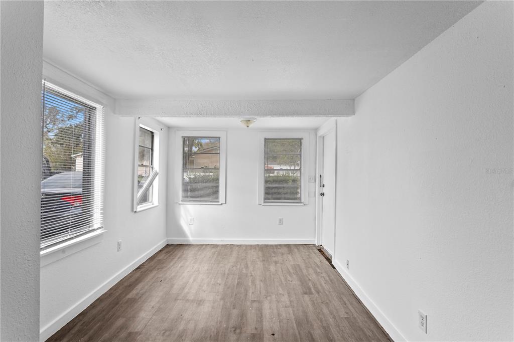 An empty room with white walls, wood-look flooring, and several windows with blinds — 4103 N HOWARD AVENUE UNIT A, TAMPA, FL
