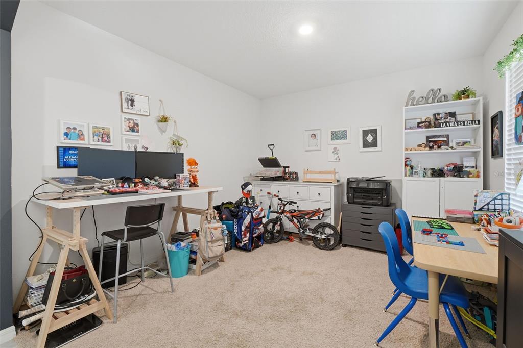 A home office or playroom with two desks, a bookshelf, a bicycle, and carpeted flooring — 2609 GRAND CENTRAL AVENUE, TAVARES, FL