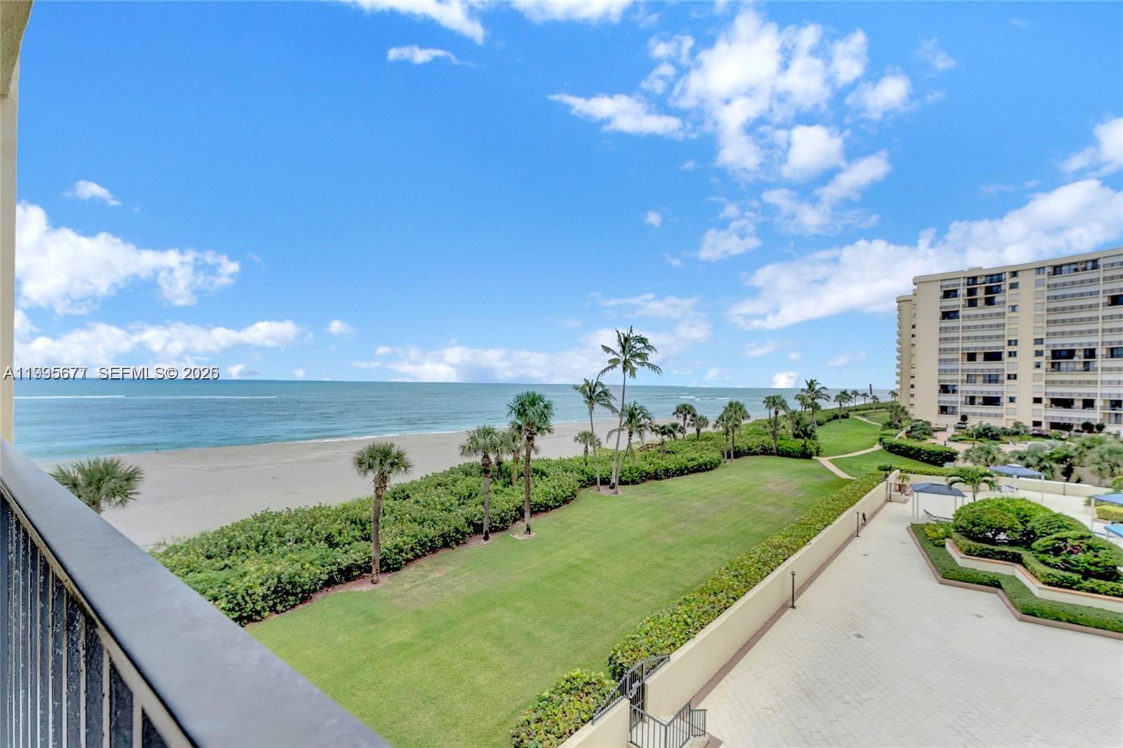 An elevated view of a grassy lawn, palm trees, beach, and ocean from a balcony — 400 Ocean Trail Way # 401, Jupiter FL 33477, JUPITER, FL