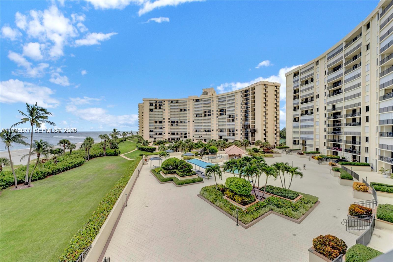An elevated view shows a beachside apartment complex with a pool, landscaping, and oceanfront lawn — 400 Ocean Trail Way # 401, Jupiter FL 33477, JUPITER, FL