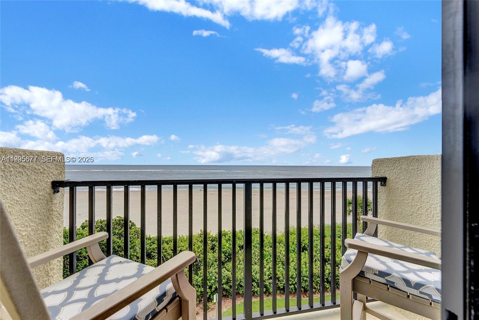 A balcony with two chairs overlooks a sandy beach and the ocean under a sky — 400 Ocean Trail Way # 401, Jupiter FL 33477, JUPITER, FL